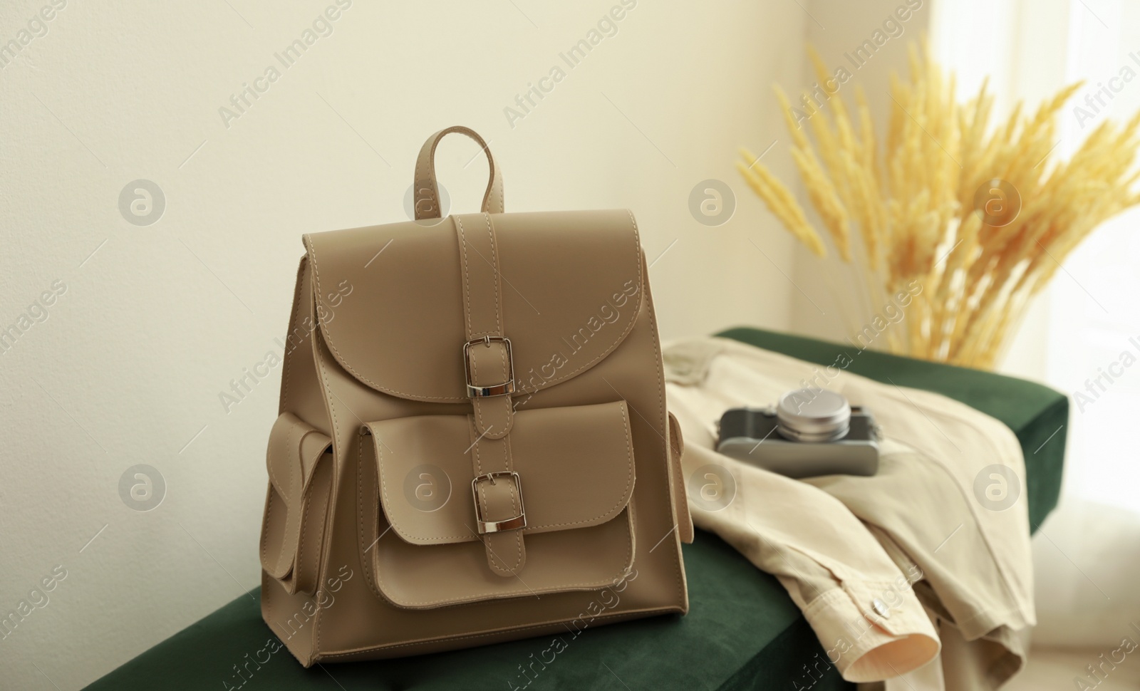 Photo of Stylish beige backpack and jacket on green bench indoors