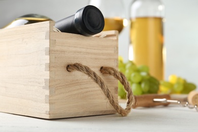 Photo of Wooden crate with bottle of wine on white table