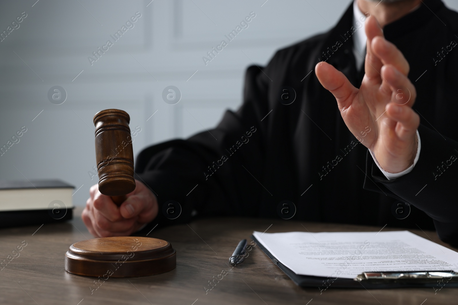 Photo of Judge with gavel and papers sitting at wooden table, closeup