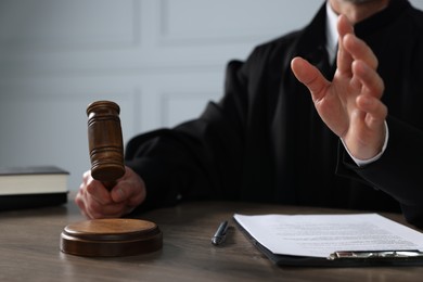 Judge with gavel and papers sitting at wooden table, closeup
