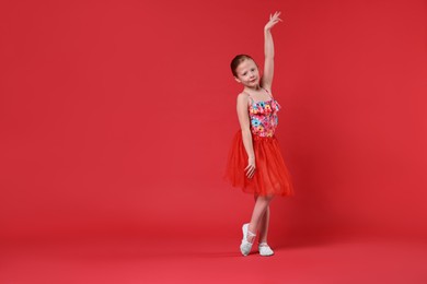 Cute little girl dancing on red background, space for text