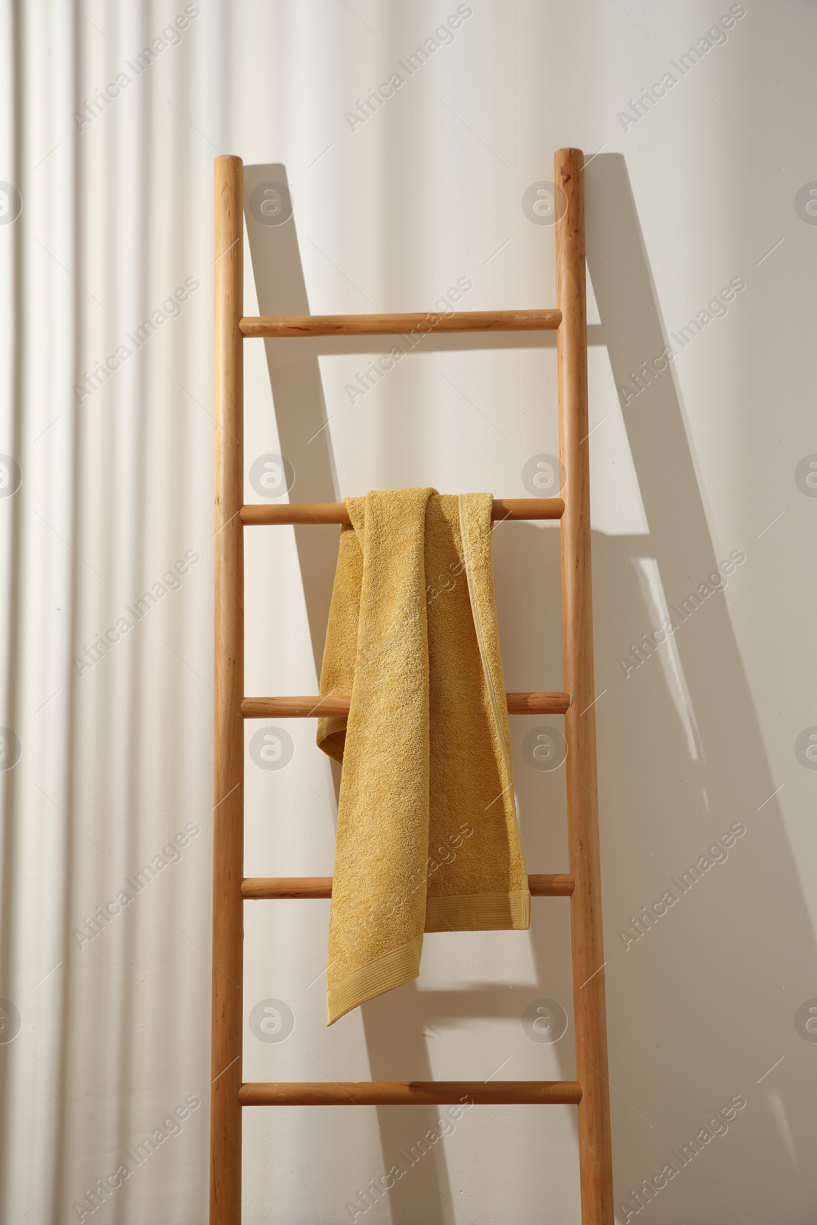 Photo of Yellow towel hanging on wooden ladder indoors