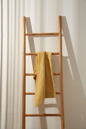 Photo of Yellow towel hanging on wooden ladder indoors