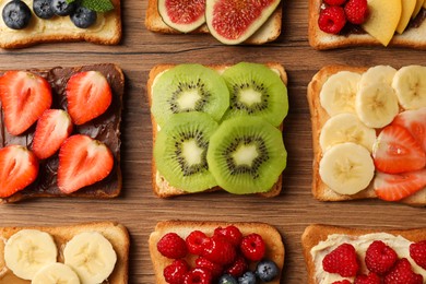 Tasty toasts with different spreads and fruits on wooden table, flat lay