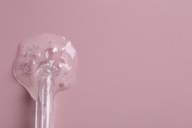 Photo of Pipette with cosmetic serum on pink background, top view. Space for text