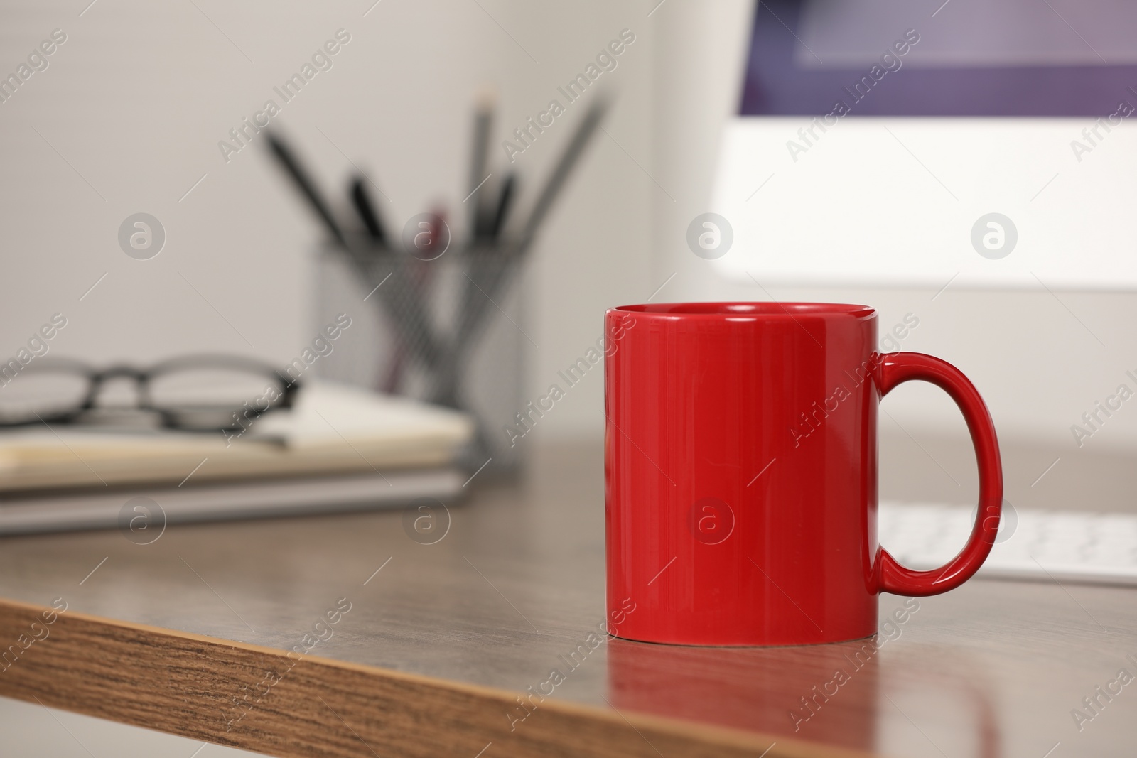 Photo of Red ceramic mug on wooden table at workplace. Space for text