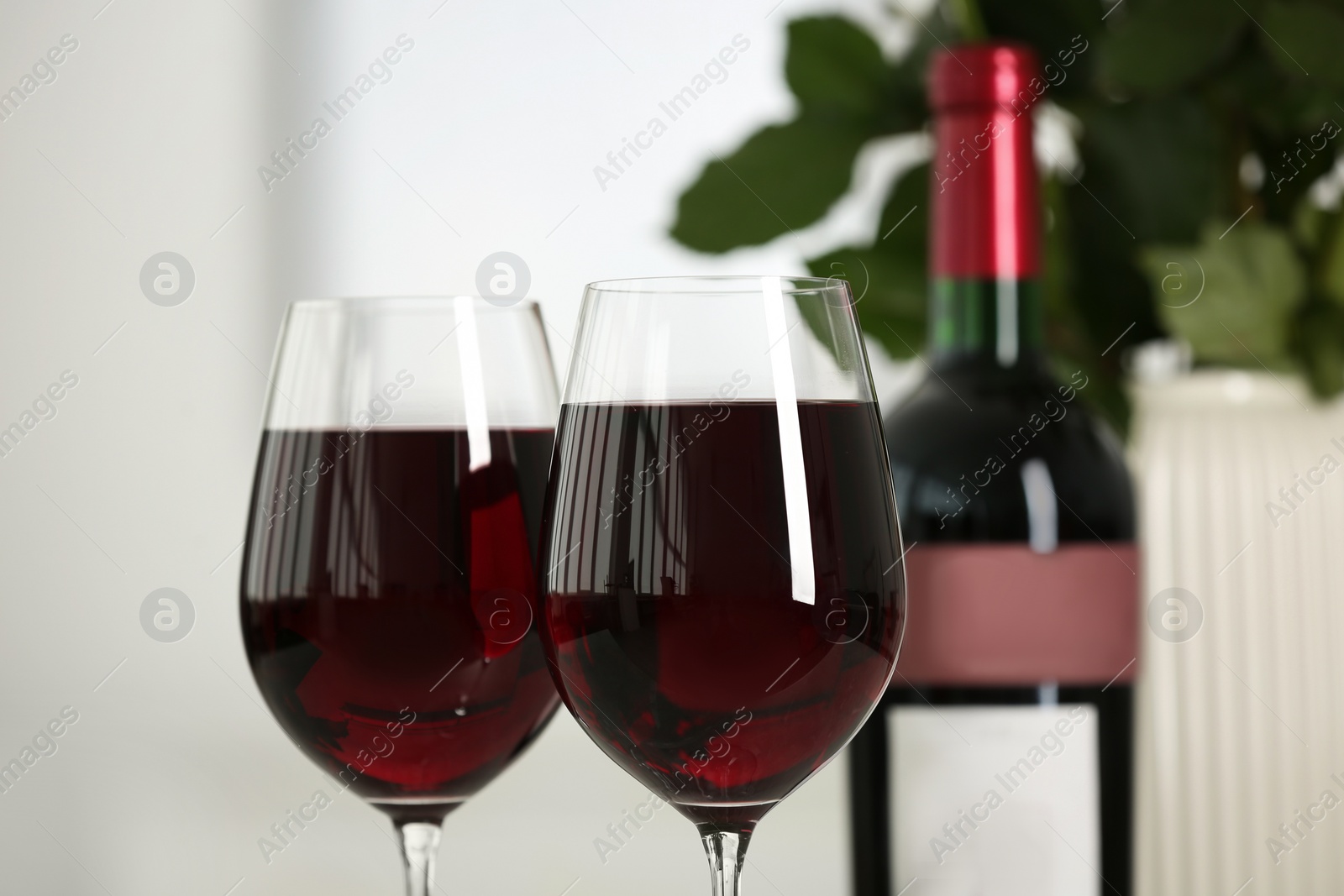 Photo of Glasses of delicious red wine on blurred background, closeup. Romantic date