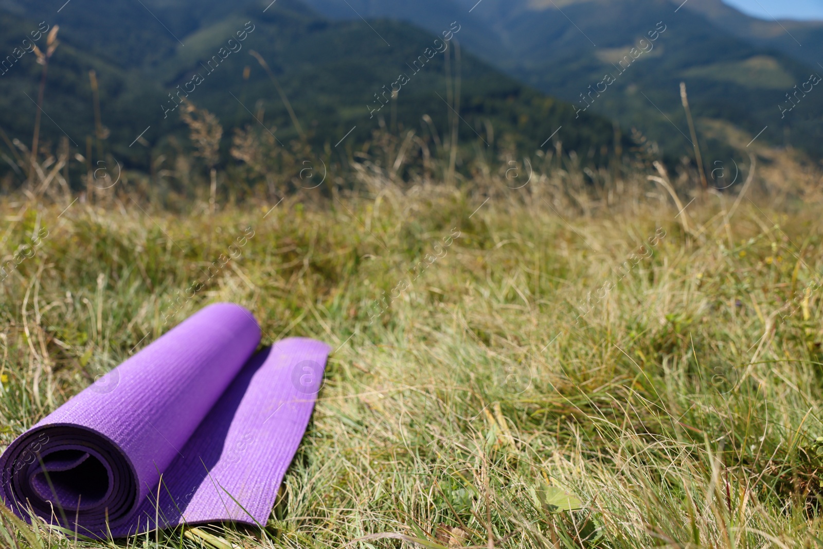 Photo of Rolled sleeping pad on grass in mountains, space for text