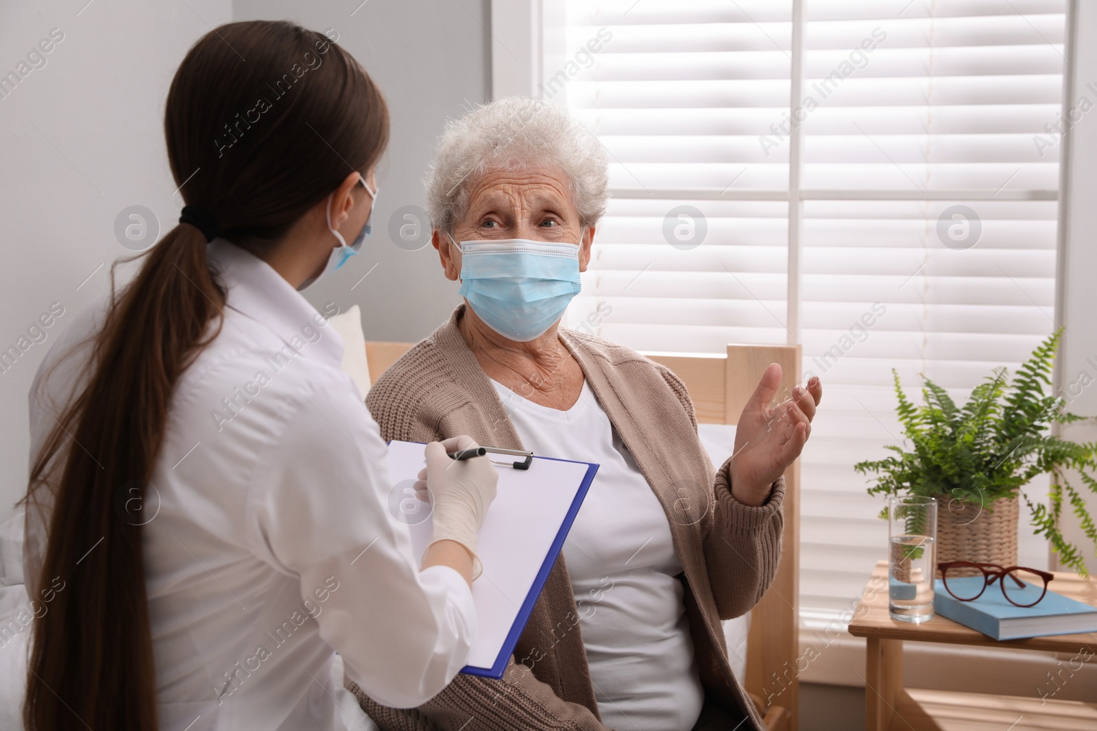 Photo of Doctor examining senior woman with protective mask at nursing home