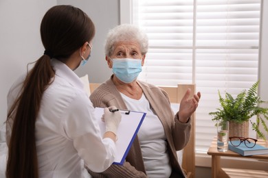 Photo of Doctor examining senior woman with protective mask at nursing home