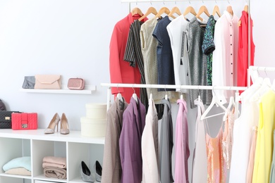 Photo of Racks with stylish clothes in light room