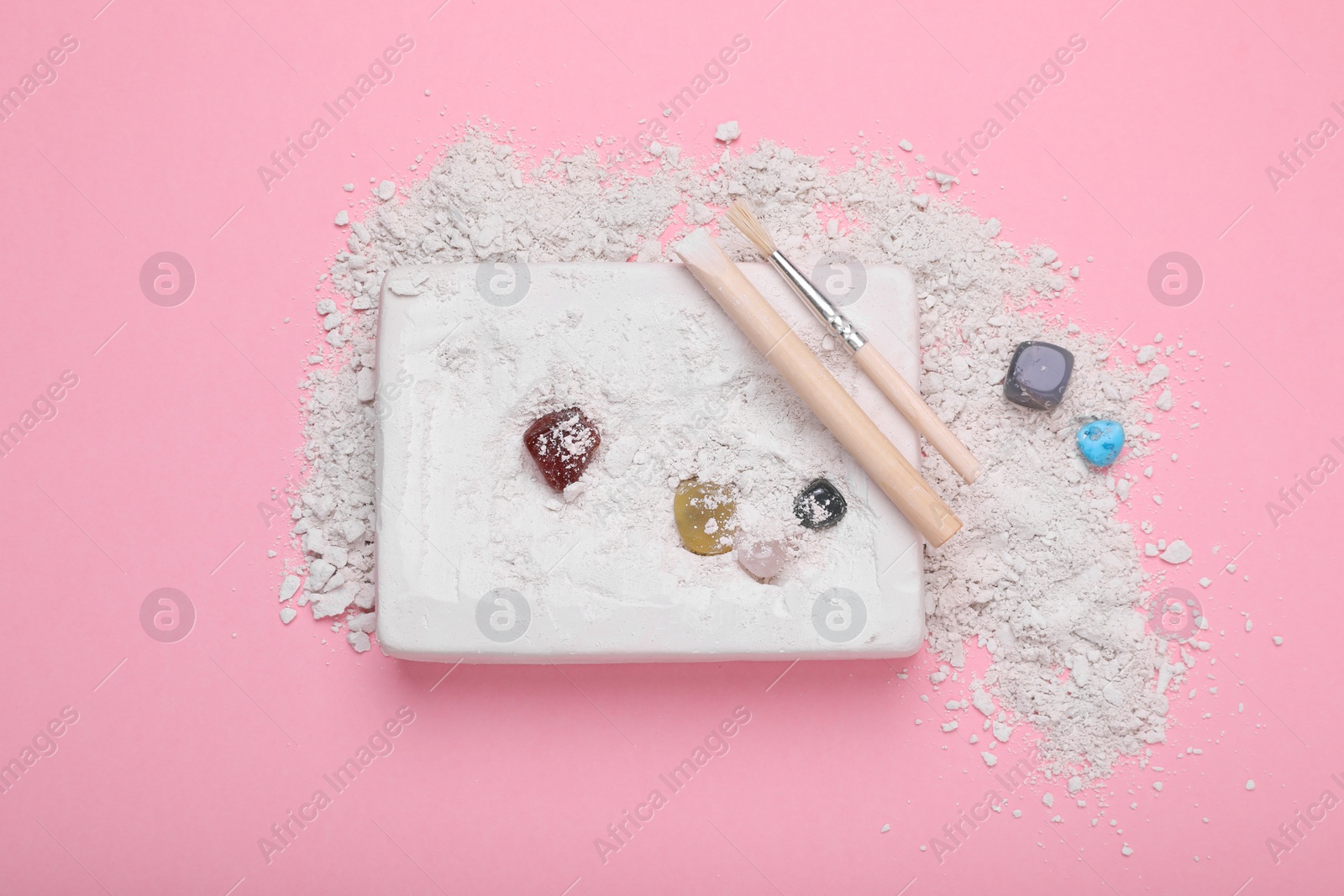 Photo of Excavation kit on pink background, top view. Educational toy for motor skills