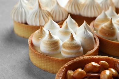 Photo of Many different tartlets on light grey table, closeup. Tasty dessert