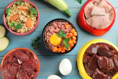 Photo of Pet food and natural ingredients on light blue wooden table, flat lay