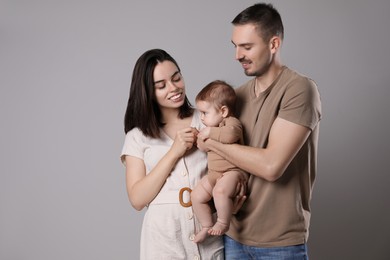 Photo of Happy family. Couple with their cute baby on grey background