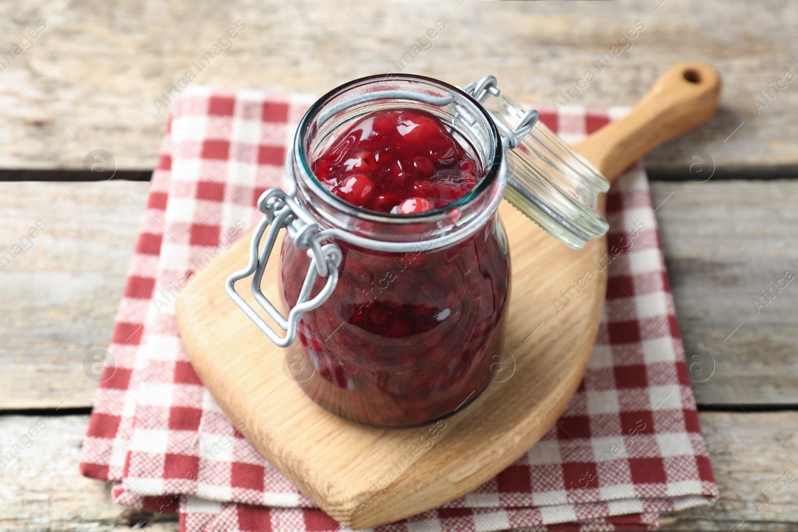 Photo of Fresh cranberry sauce in glass jar on light wooden table