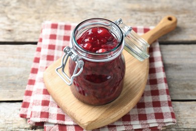 Fresh cranberry sauce in glass jar on light wooden table