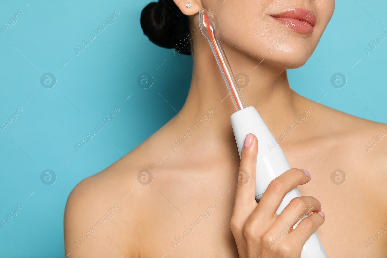 Photo of Woman using high frequency darsonval device on light blue background, closeup. Space for text