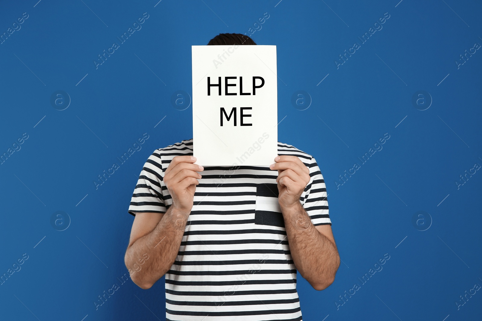 Image of Man holding paper with text HELP ME on blue background