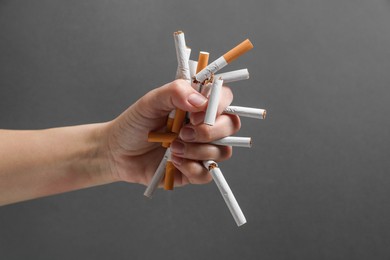 Stop smoking. Woman holding broken cigarettes on grey background, closeup