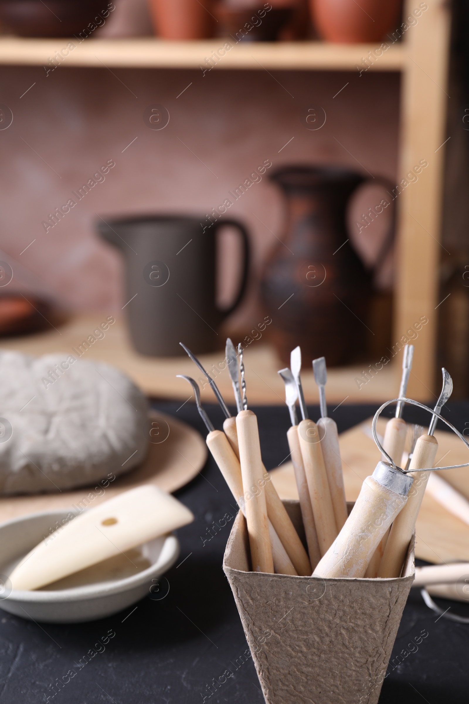 Photo of Clay and set of modeling tools on table in workshop