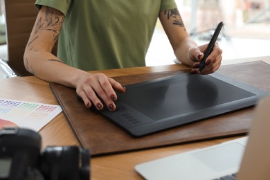 Photo of Professional designer with graphic tablet at wooden table, closeup