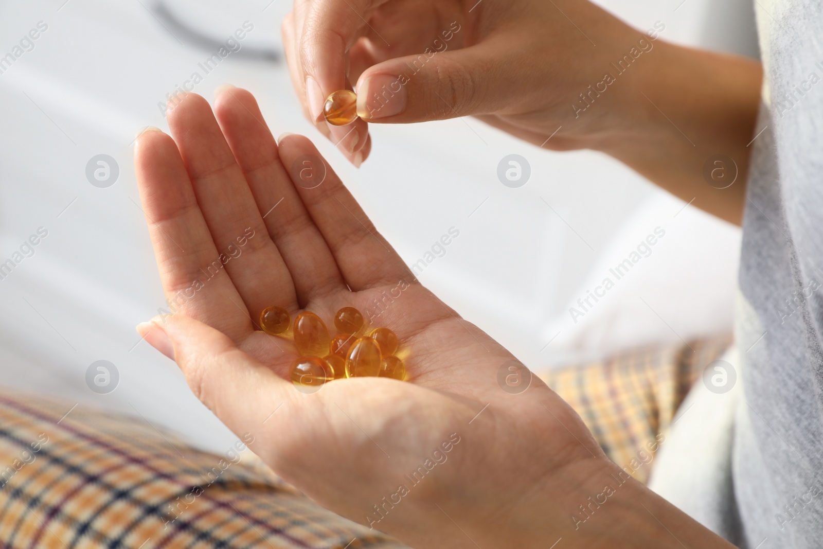 Photo of African-American woman with vitamin capsules at home, closeup