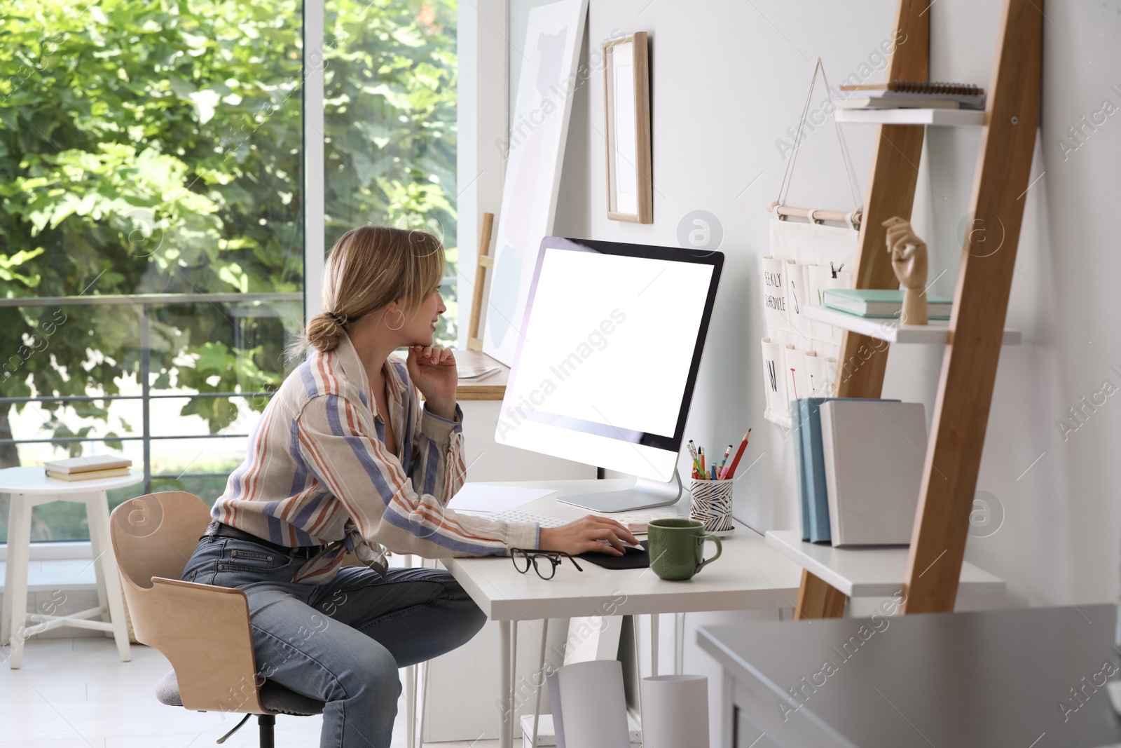 Photo of Young woman working on computer at table in room