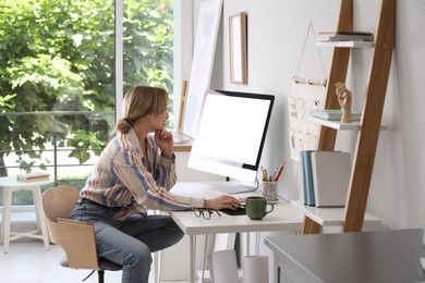 Young woman working on computer at table in room