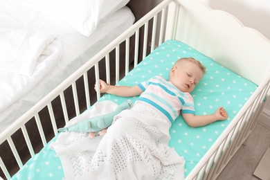 Cute little child sleeping in crib at home