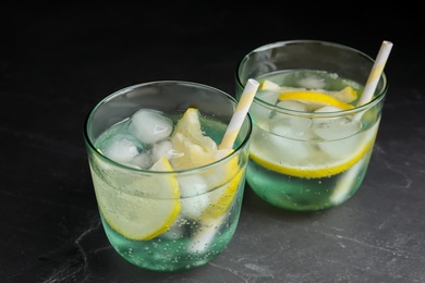 Photo of Soda water with lemon slices and ice cubes on grey table