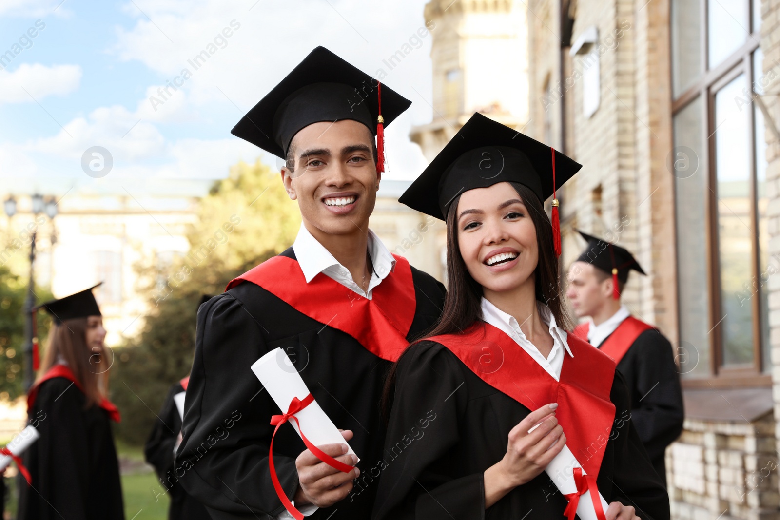 Photo of Happy students with diplomas outdoors. Graduation ceremony