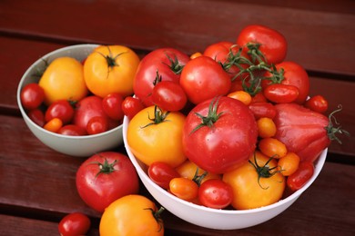Photo of Bowls with fresh tomatoes on wooden table