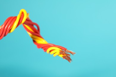 Photo of Electrical wires on light blue background, closeup. Space for text