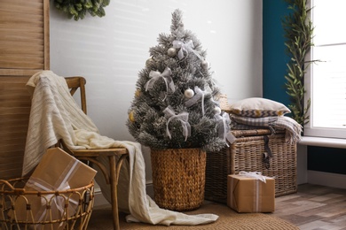Photo of Stylish room interior with beautiful Christmas tree near white wall