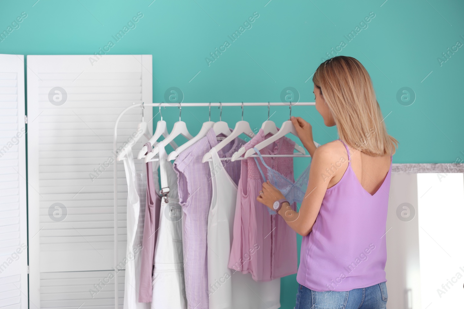 Photo of Young woman near clothes rack indoors. Stylish dressing room interior