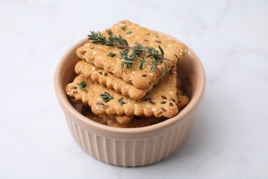 Photo of Cereal crackers with flax, sesame seeds and thyme in bowl on white table, closeup