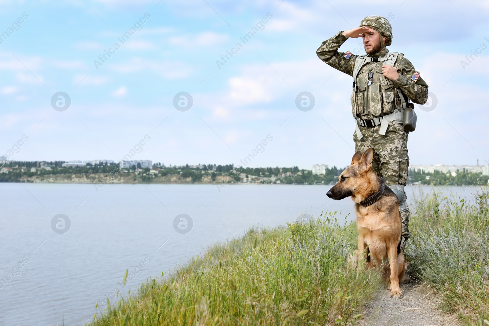 Photo of Man in military uniform with German shepherd dog outdoors