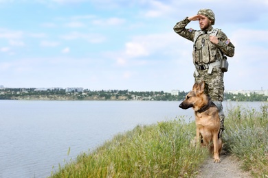 Man in military uniform with German shepherd dog outdoors