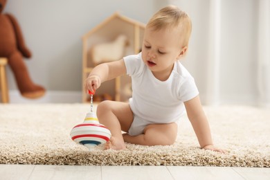 Children toys. Cute little boy playing with spinning top on rug at home