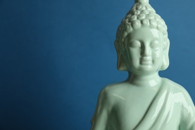 Beautiful ceramic Buddha sculpture on blue background. Space for text