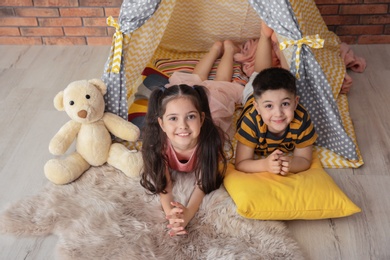 Photo of Playful little children in handmade tent indoors