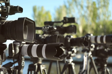 Photo of Modern professional video cameras outdoors on sunny day, closeup