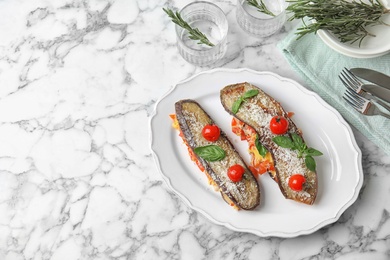 Baked eggplant with tomatoes, cheese and basil on marble table. Space for text