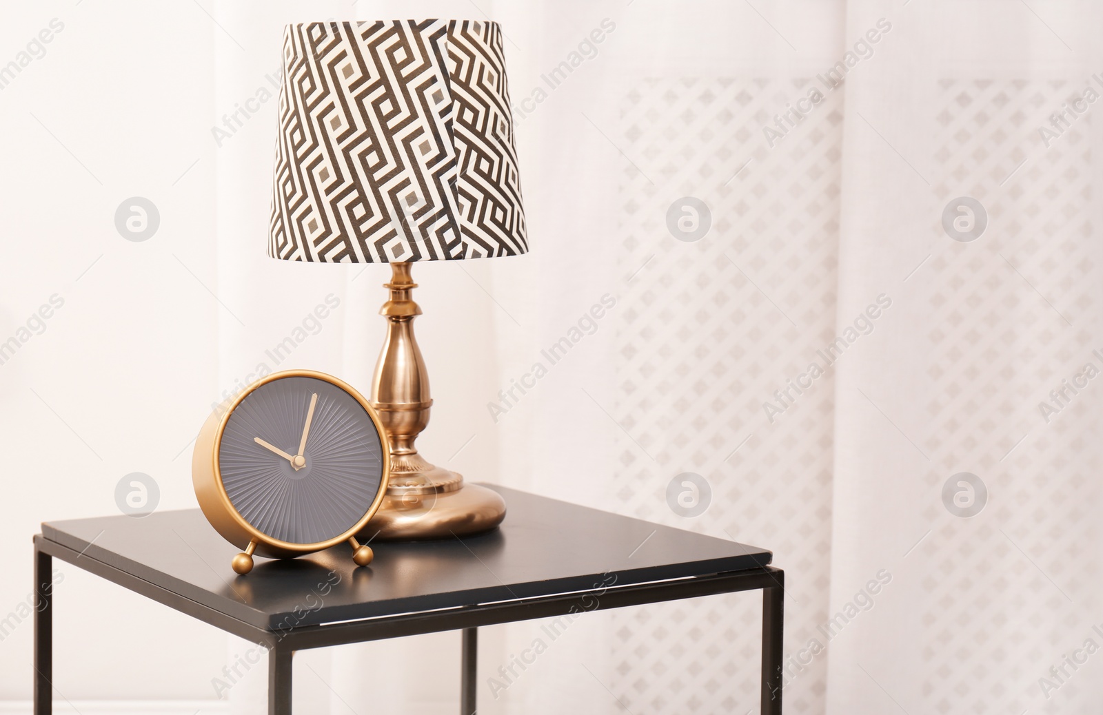 Photo of Analog clock and lamp on table indoors, space for text. Time of day
