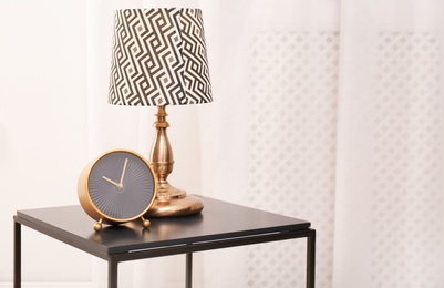 Analog clock and lamp on table indoors, space for text. Time of day