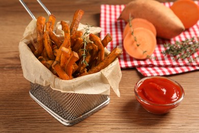 Photo of Sweet potato fries and ketchup on wooden table, closeup