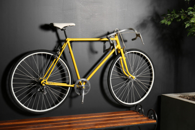 Photo of Yellow bicycle hanging on black wall indoors