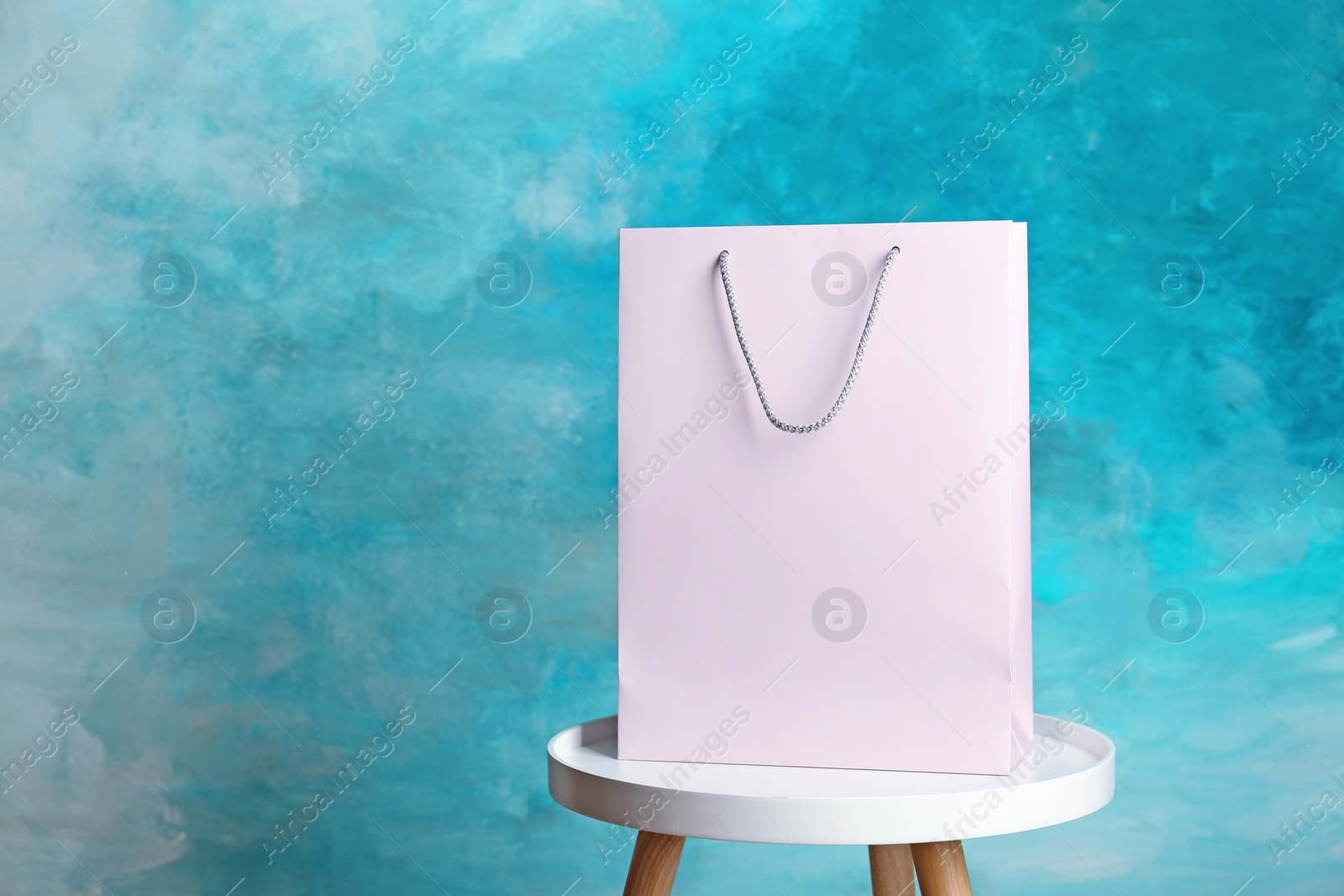 Photo of Mockup of paper shopping bag on table against color background