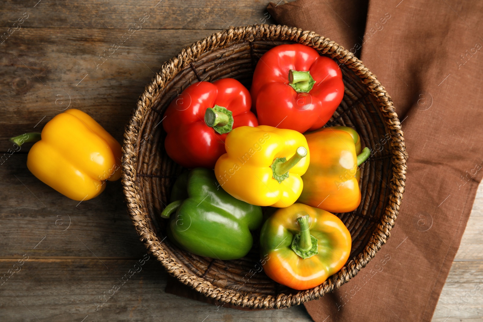 Photo of Bowl with ripe paprika peppers on wooden background, top view